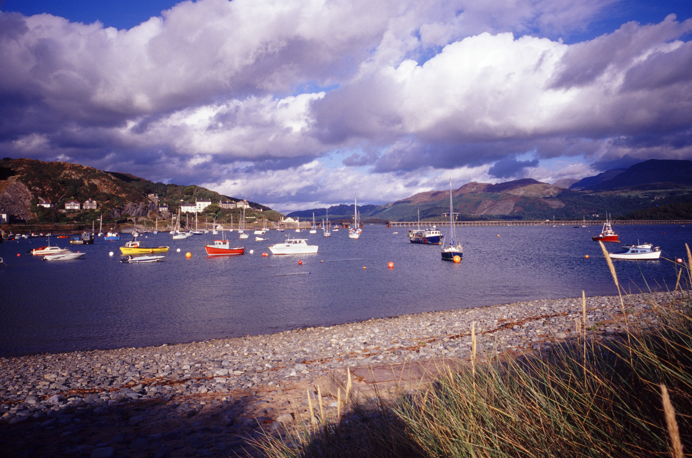 an image of Boats moored in the sheltered water of the harbour at Barmouth, Wales in a picturesque landscape view