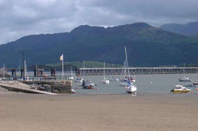 Barmouth rail viaduct with small fishing and pleasure boats moored in the sheltered harbour in the foreground