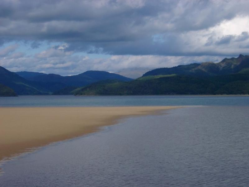 Tranquil Waterside with Brown Sand, Captured with Mountains View