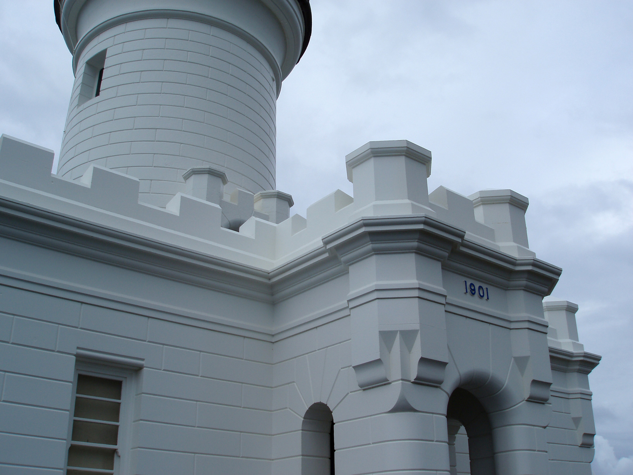 an image of Close up Vintage White Byron Bay Lighthouse Structure on Lighter Blue Gray Sky Background.