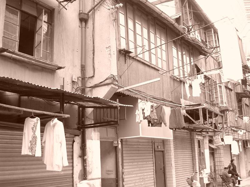 Sepia view of a typical Chinese street scene with residential apartments and washing hanging out to dry on the facades of buildings with people chatting in the street