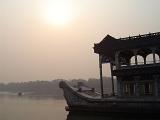 Ornate Chinese house boat with an upper arched covered viewing deck and living quarters below on a tranquil misty lake