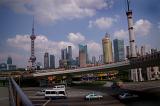 Shanghai streets and skyline showing traffic, the road infrastructure and tall modern design skyscrapers of the CBD under a cloudy blue sky in a travel and lifestyle concept