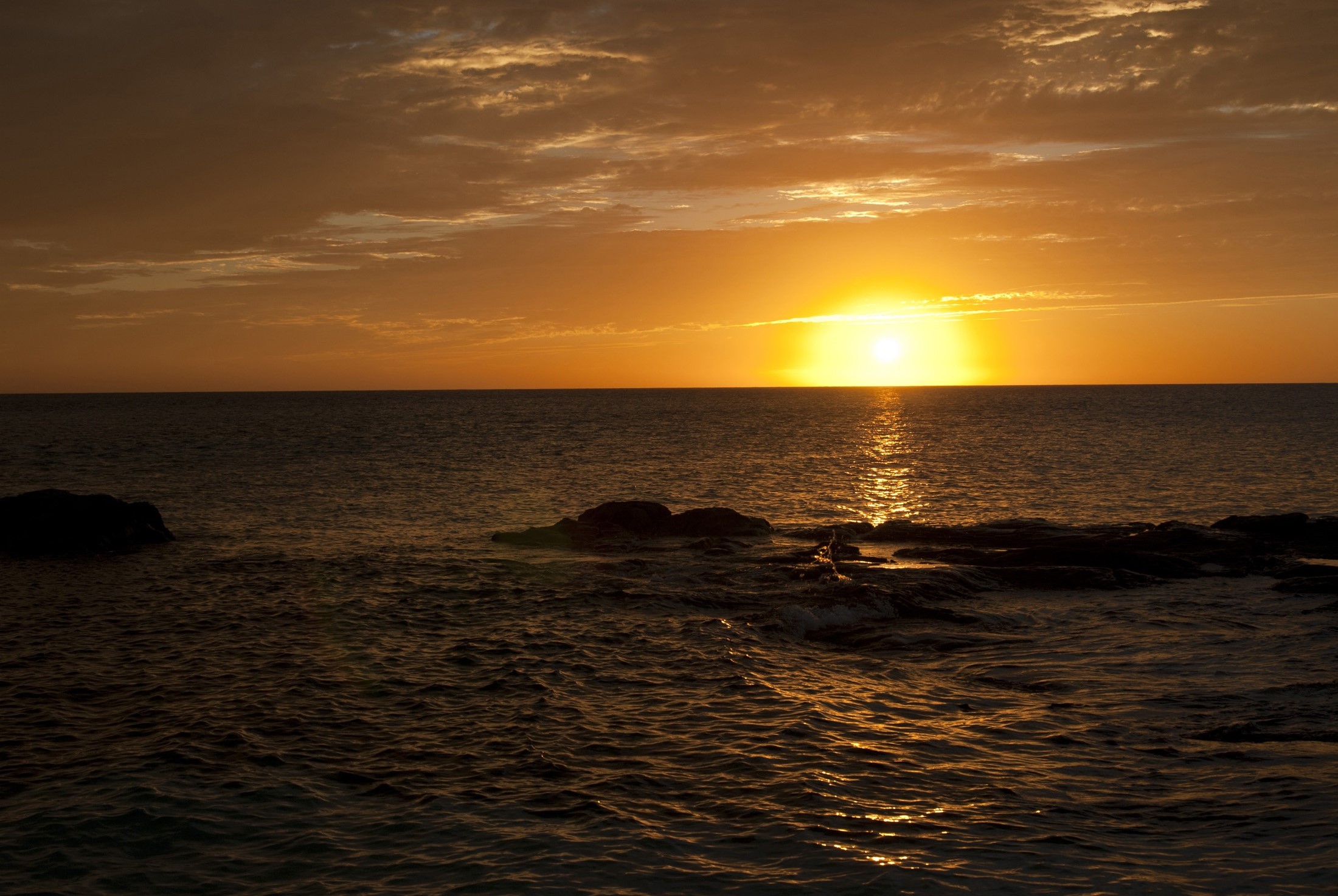 an image of Vivid sunset over the calm ocean as the orange orb of the sun just dips below the horizon