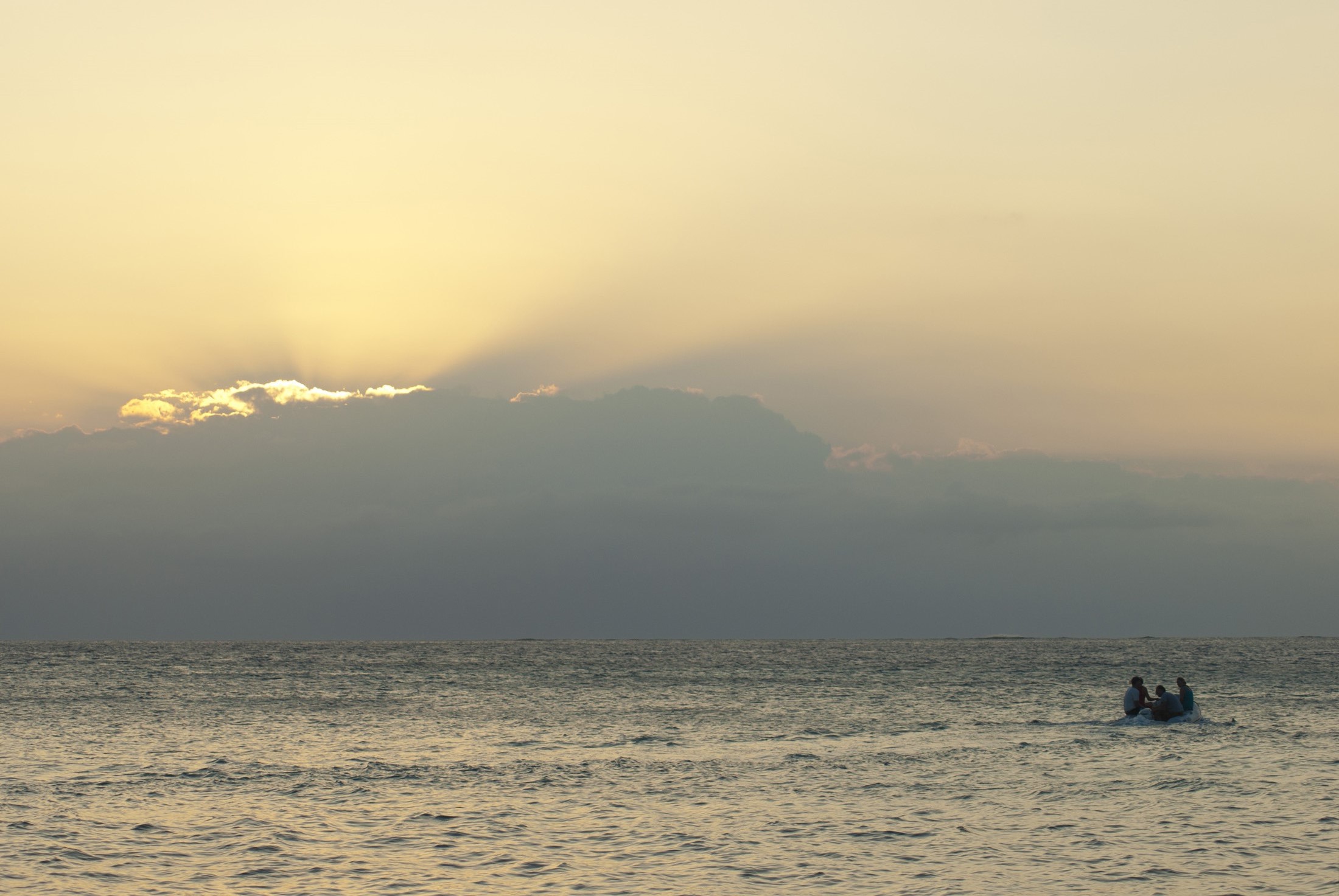 an image of Atmospheric shot of a small Fijian island boat in mid ocean with the suns rays piercing the clouds
