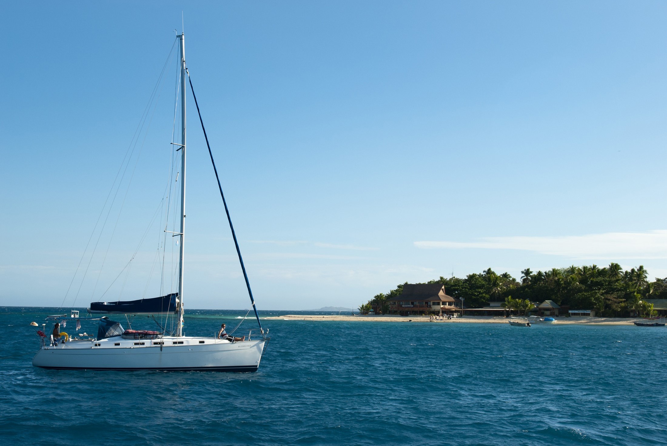 an image of Luxury pleasure yacht at Beachcomber Island, Fiji with thatched beach umbrellas visible on the beach