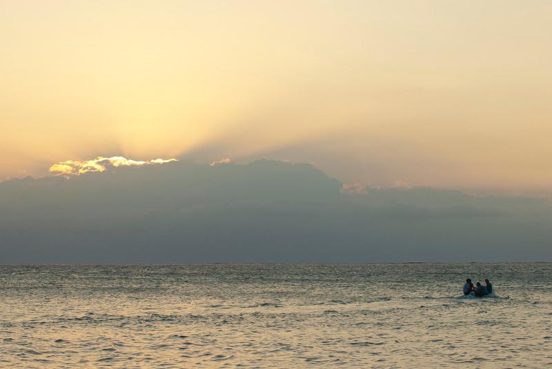 Atmospheric shot of a small Fijian island boat in mid ocean with the suns rays piercing the clouds
