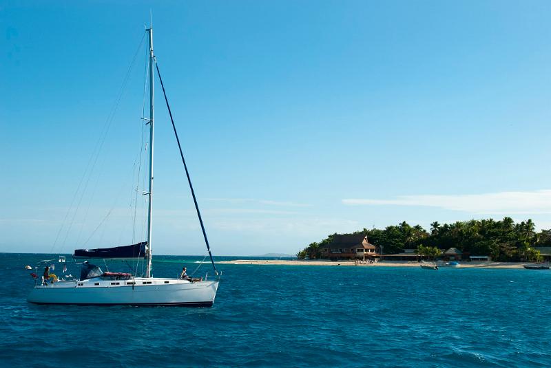 Luxury pleasure yacht at Beachcomber Island, Fiji with thatched beach umbrellas visible on the beach