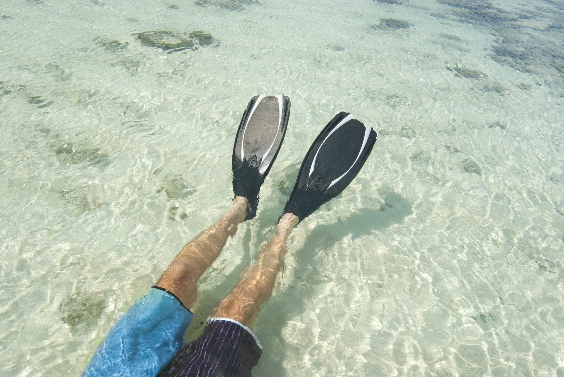 an image of Man lying on his back wearing a pair of fins snorkeling in clear tropical water off a Fijian island
