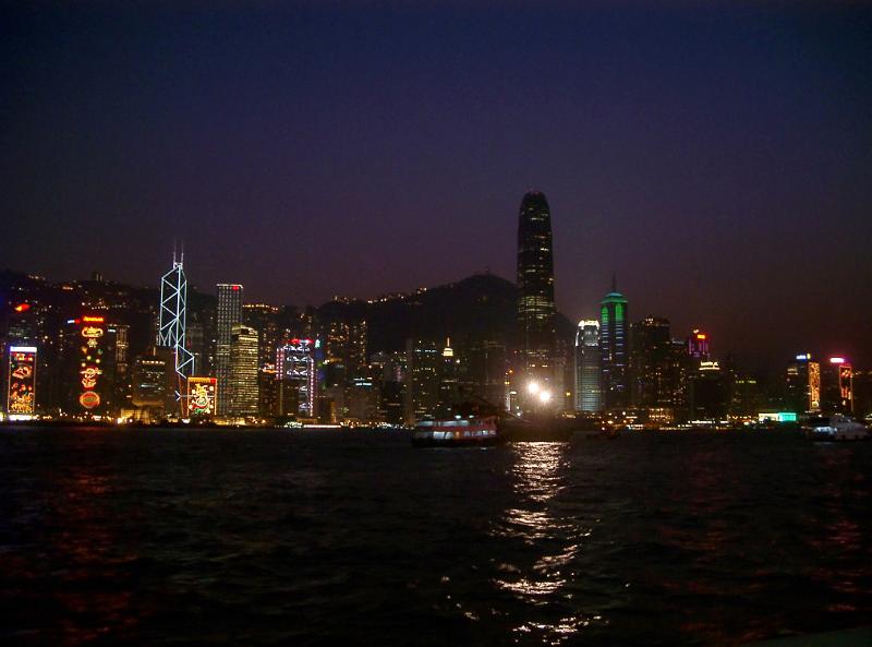 Cityscape of Kong at night with the buildings of the CBD illuminated and casting reflections across the water
