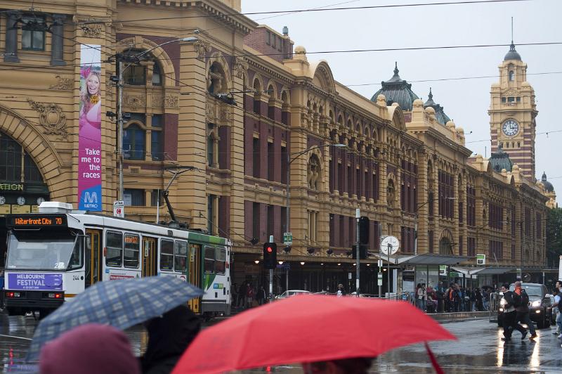 A busy winter scene and umbrellas on Flinders street in Melbourne city, Australia.