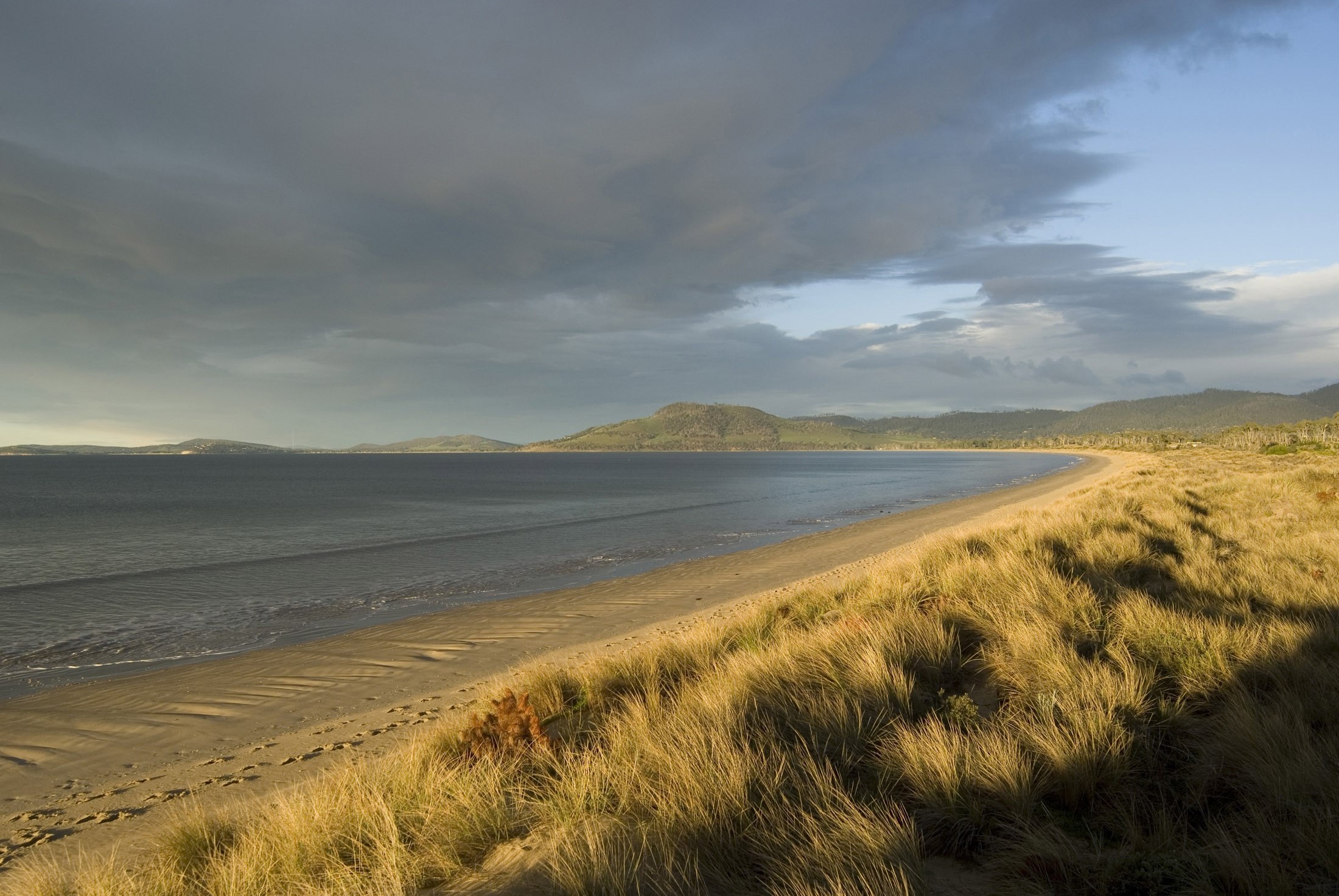an image of early evening with dark storm clouds over 7 mile beach, hobart, tasmania