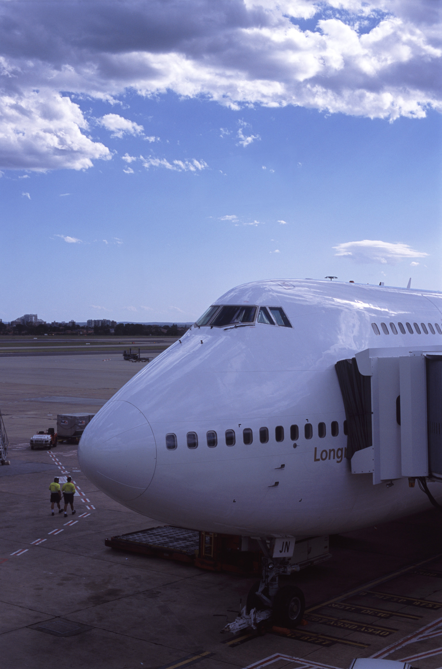 an image of 474 Jumbo aircraft loading for departure with a passenger skybridge attached to the side for embarkation as it stands on the apron at the airport