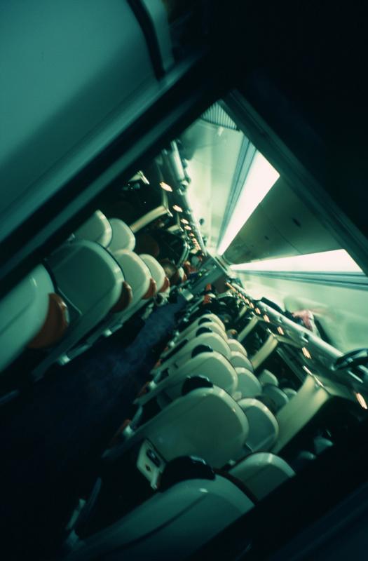 Angled view of the interior of a train carriage in motion on a cold day showing the seating from the rear