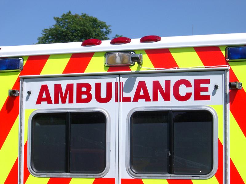 Ambulance viewed from the rear with the colorful red and yellow emergency chevron signage around the doors with the word - Ambulance