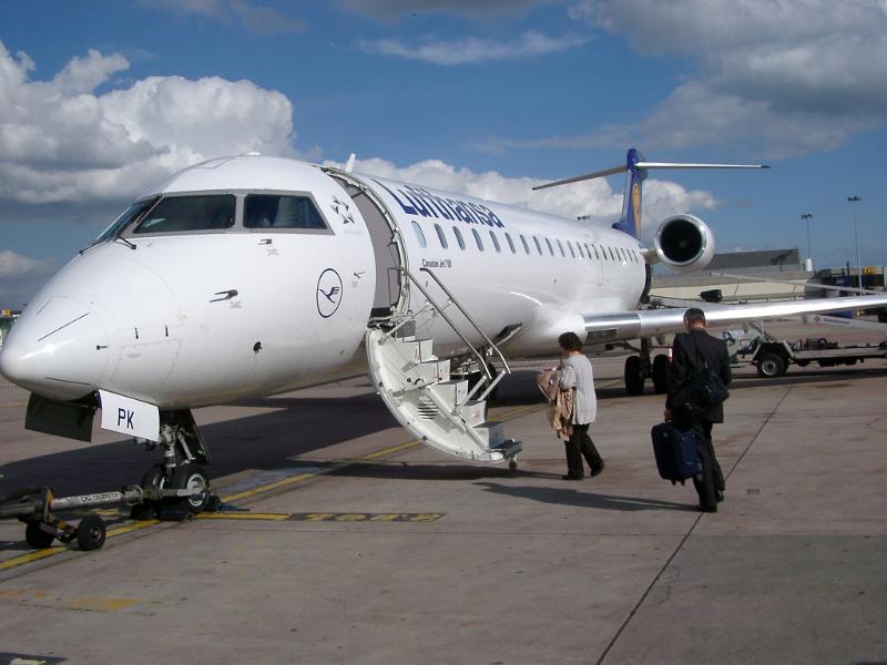 Two Passengers Boarding Small Airplane on Tarmac at Airport