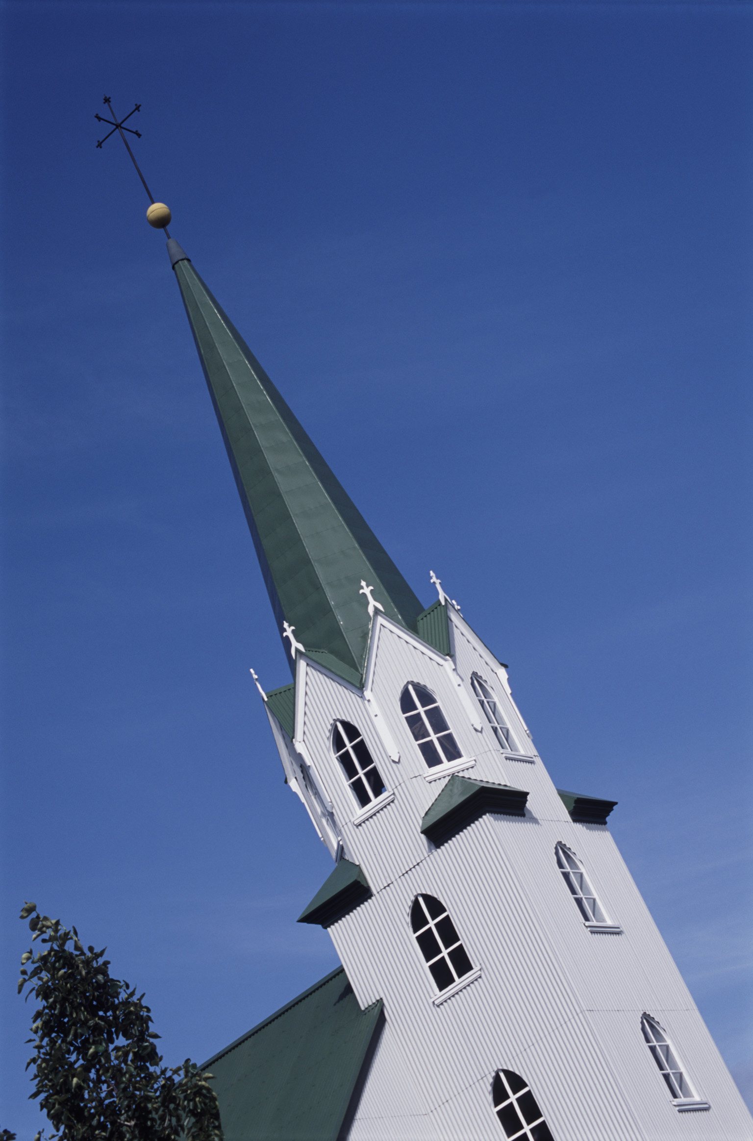 an image of Elegant church spire in Reykjavik , Iceland, with traditional architecture of a corrugated iron roof against a blue sky