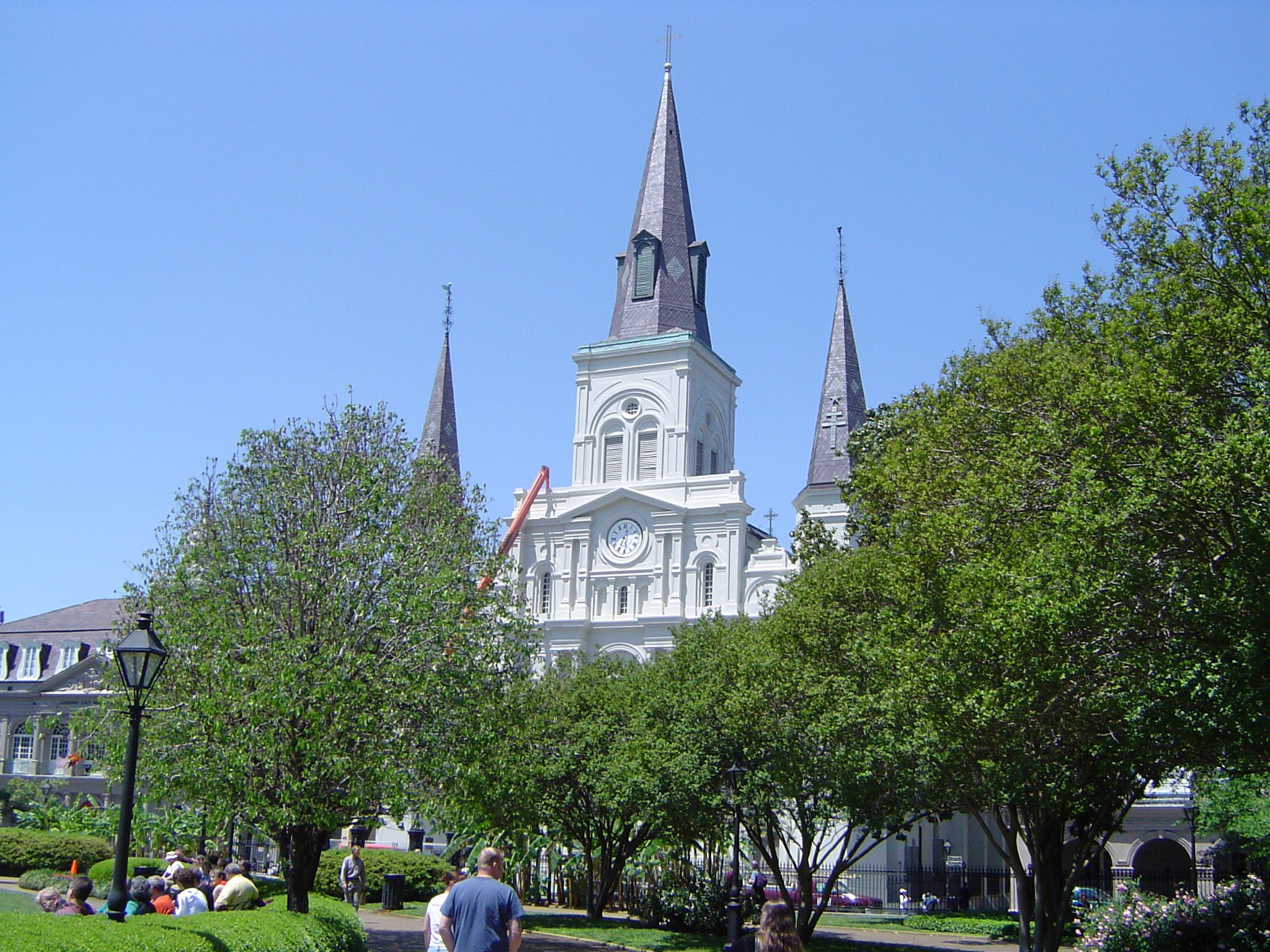 an image of Old Vintage Architectural US Christian Church with Tall Trees on Front Landscape. Isolated on Light Blue Sky Background.