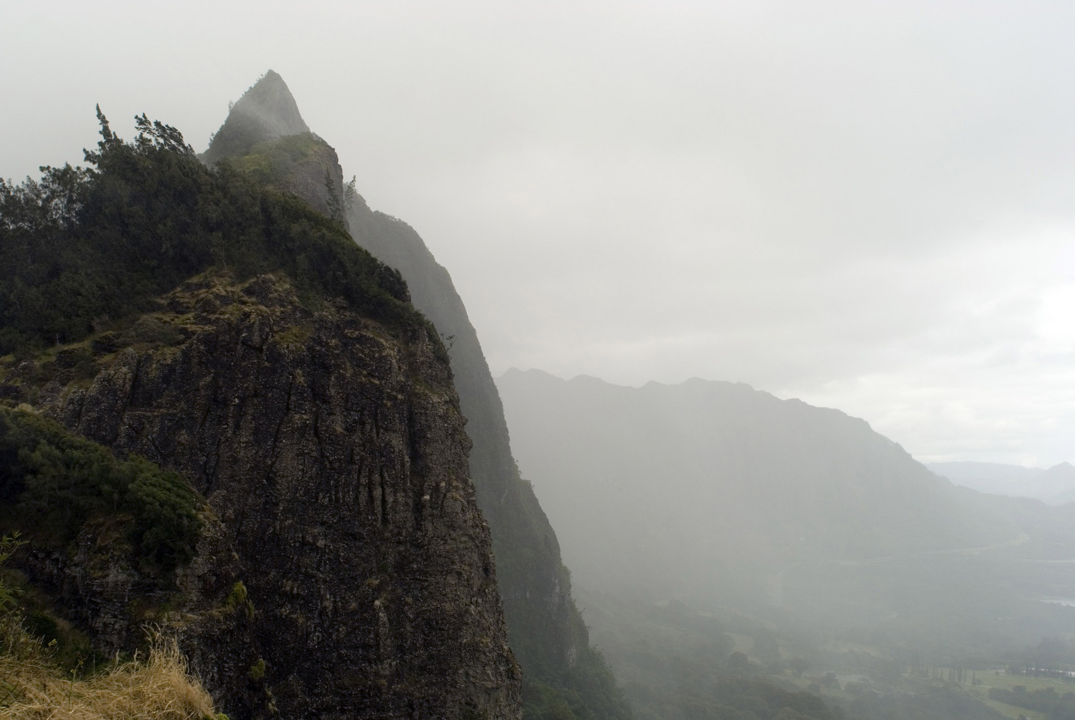 an image of Foggy Morning at Beautiful Pali Lookout. Lookout offers panoramic views of the sheer Koolau cliffs and lush Windward Coast.