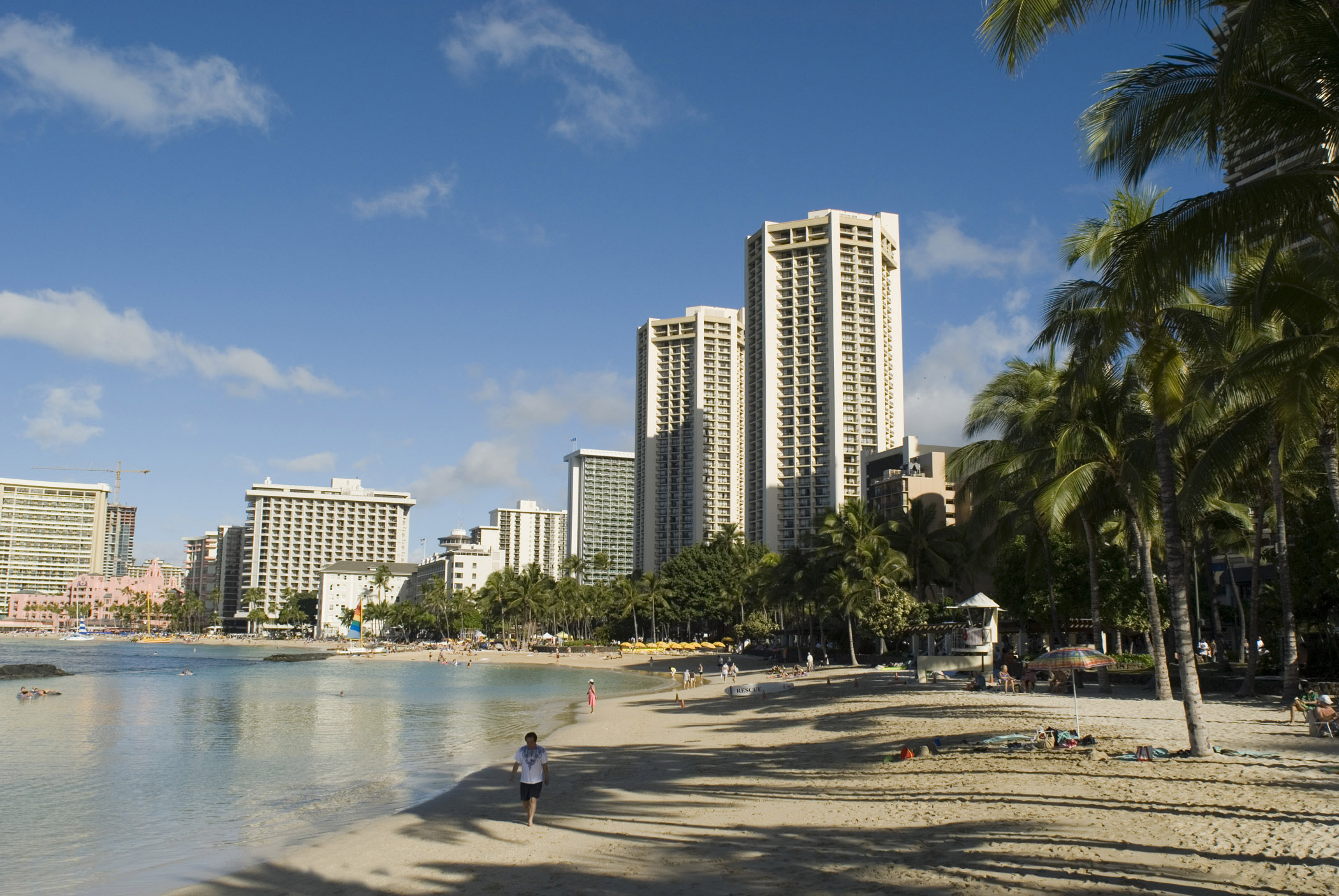 an image of Scenic view of Waikiki Beach, Hawaii with its golden sand, palm trees and high-rise apartment blocks overlooking the bay