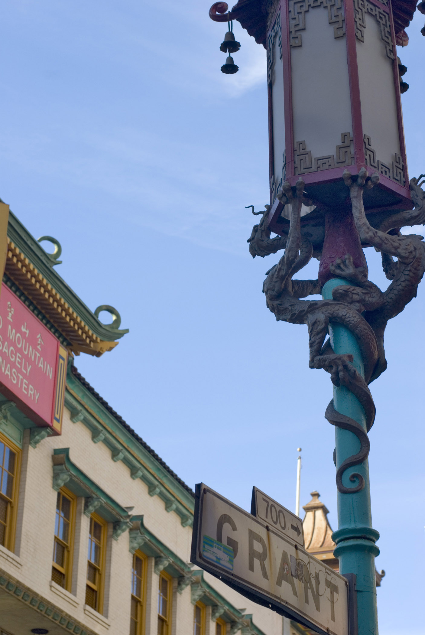 an image of Artistic Details of Decorated Street Post In Front a Vintage Building in China Town. Captured on Lighter Blue Sky Background.