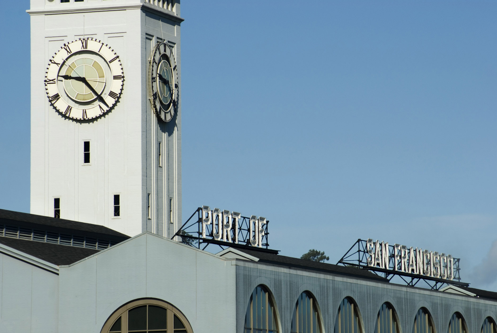 an image of Exterior Wall Clock on Building at Embarcadero San Francisco on Light Blue Sky Background.