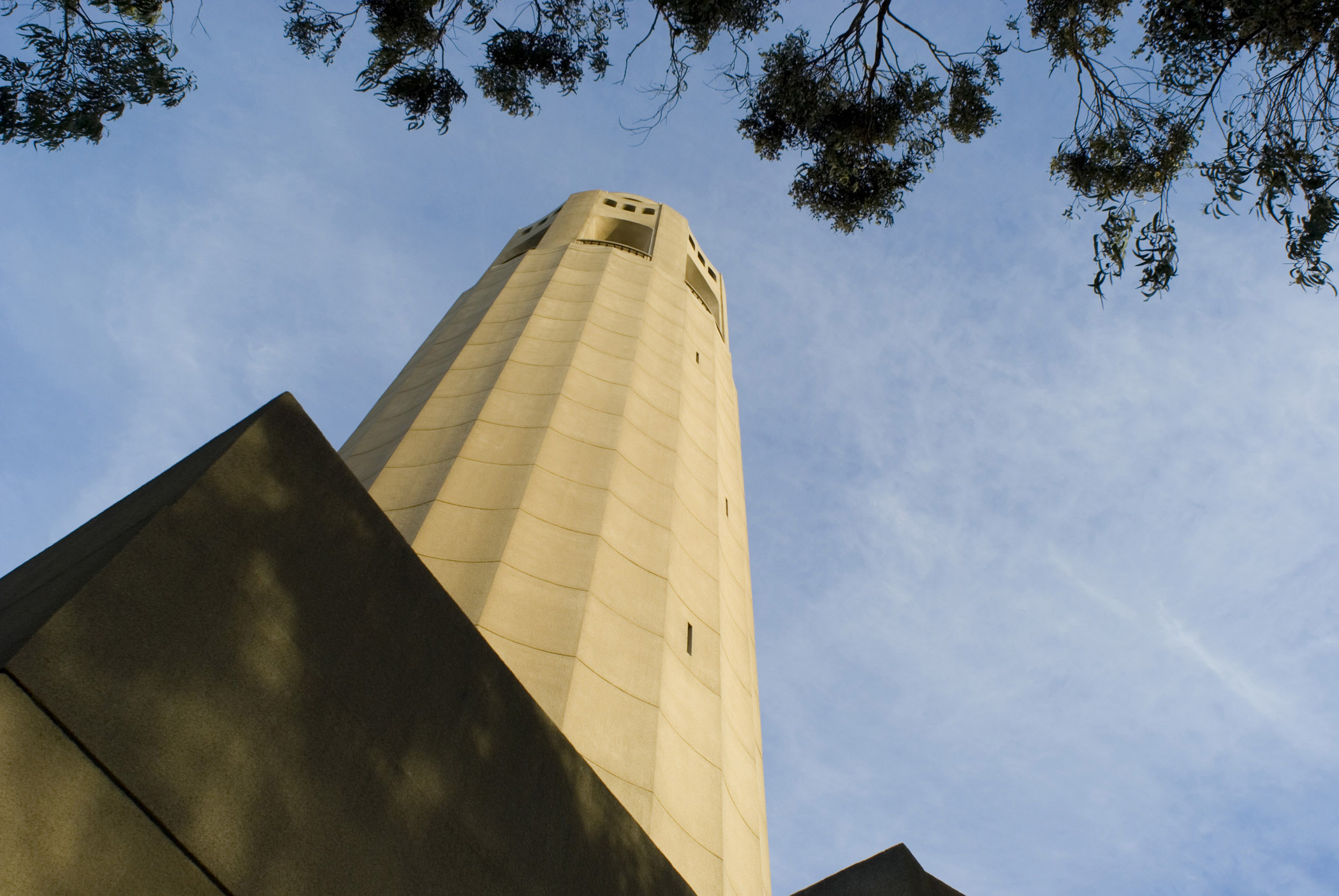 an image of Famous Old Vintage Coit Tower in Worms Eye View Isolated on Light Blue Sky Background.