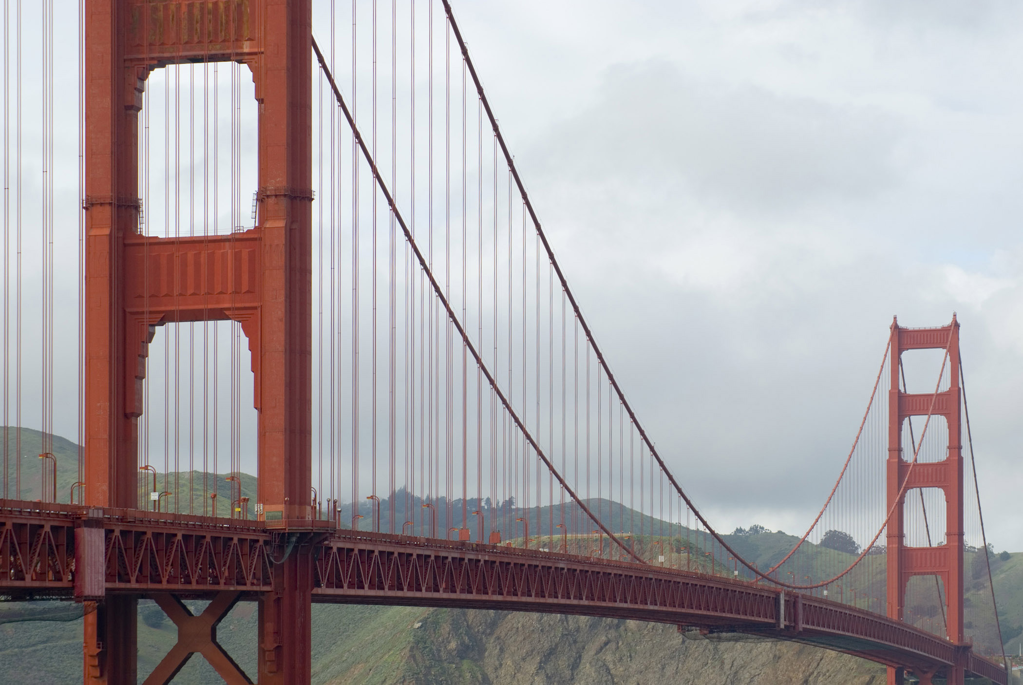 an image of View along the span and suspension cables of the icon red painted Golden Gate bridge, San Francisco crossing the San Francisco Bay on a cloudy grey day