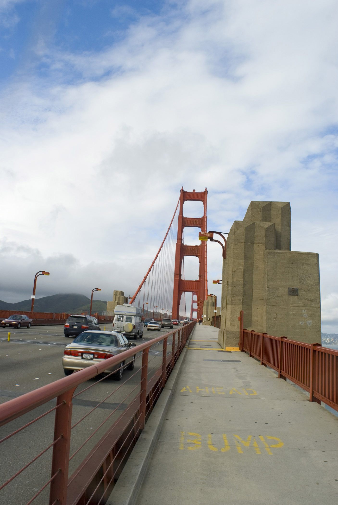 an image of Footpath along the Golden Gate Bridge, San Francisco, with traffic passing on the left and a view towards one of the support towers