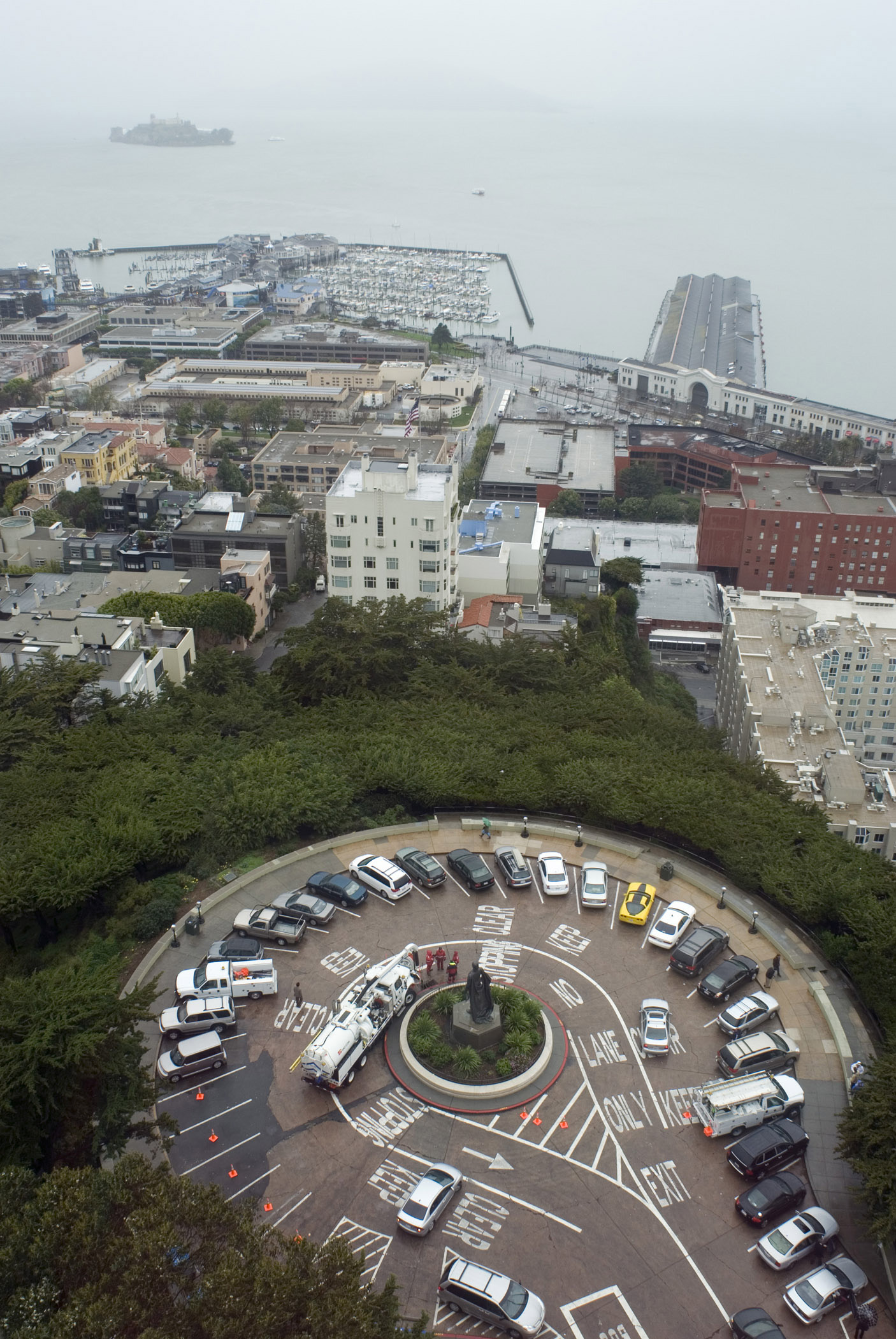 an image of Cars at Pioneer Park Turnaround Surrounded by Green Grasses and Buildings in Aerial View