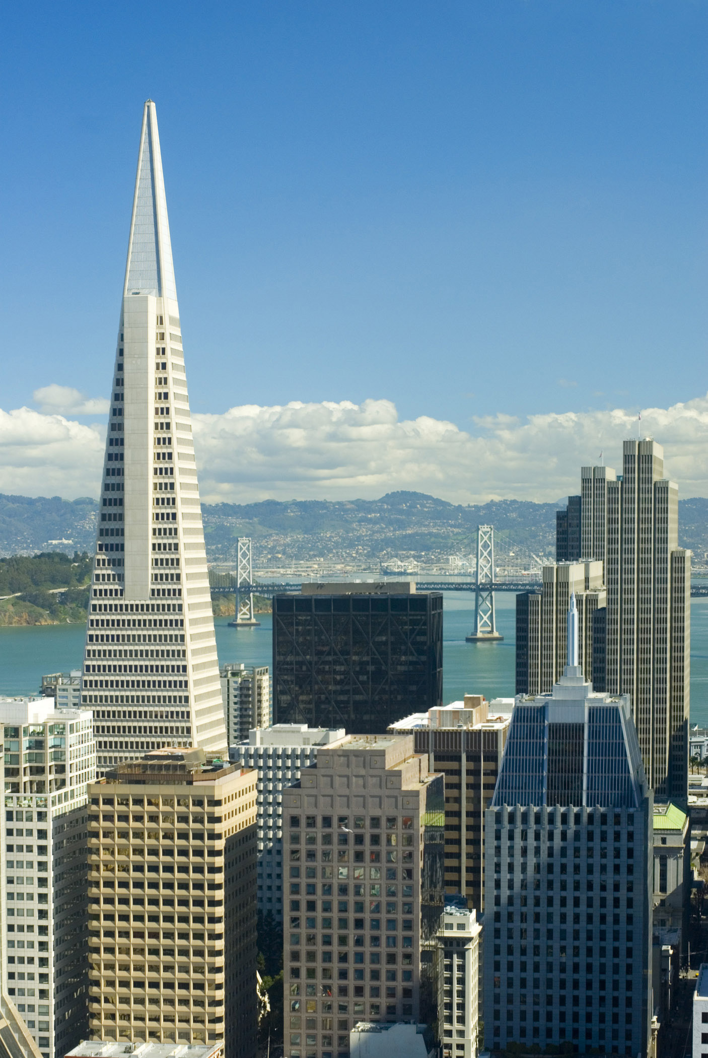 an image of Downtown San Francisco with the Transamerica Pyramid in the foreground with the skyscrapers of the CBD and a view over the bay and bridge behind
