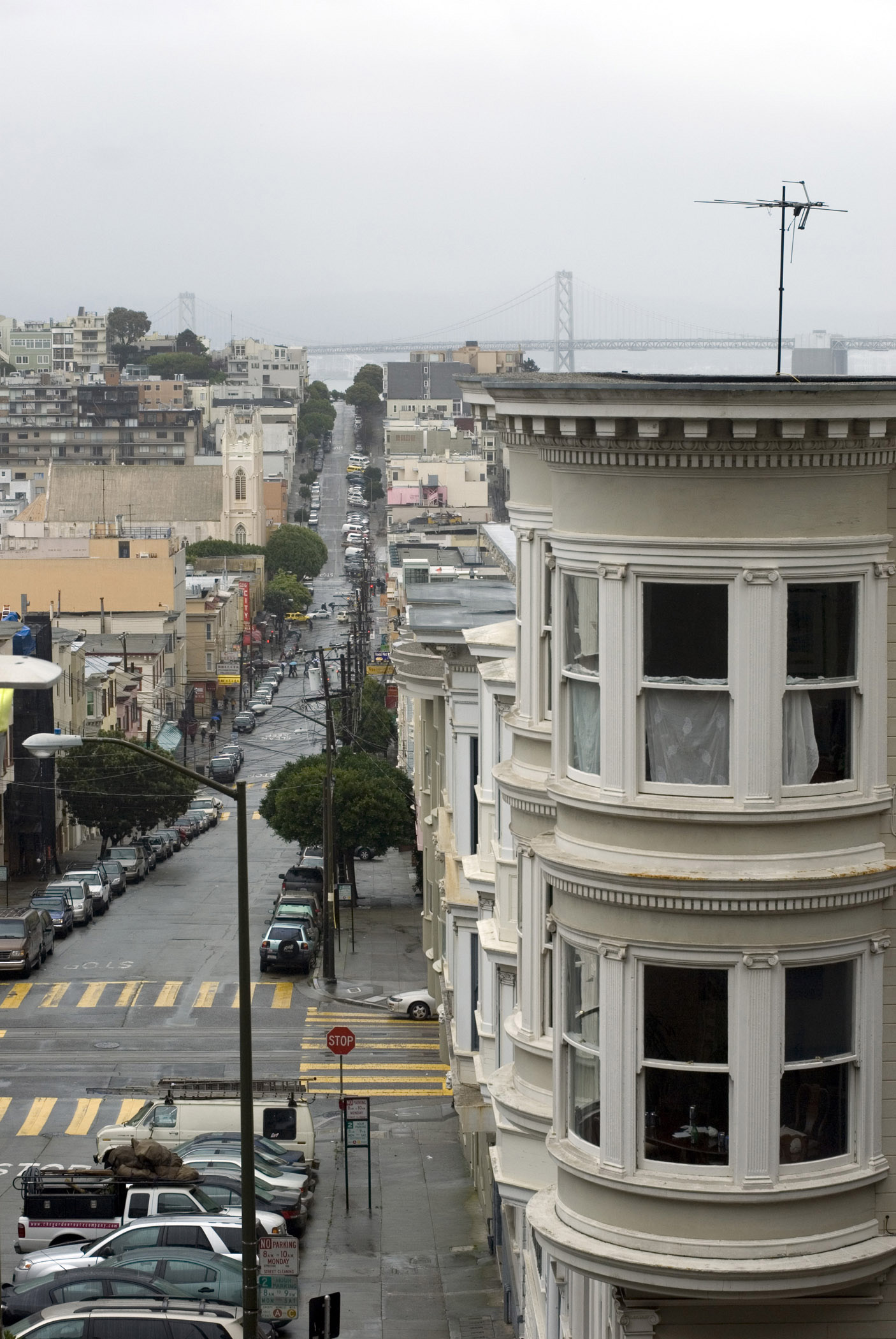 an image of Rainy day in San Francisco looking down one of the urban streets past traditional historical architecture towards the Bay