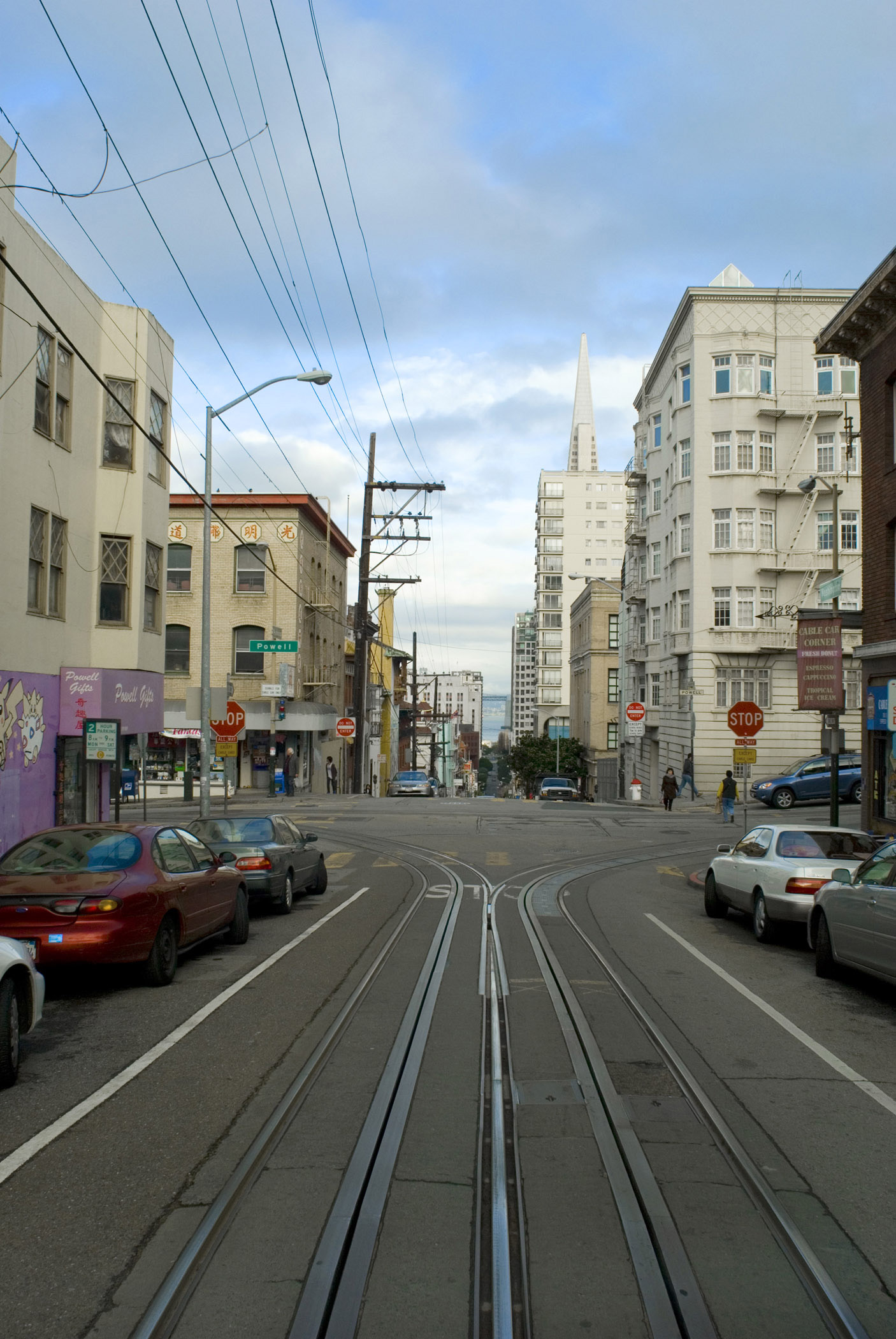 an image of Cable car ride through the streets of San Francisco with a view out of the rear of the receding tracks and architecture of the buildings