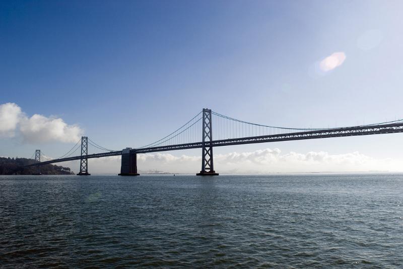 Low angle view across the water of the San Francisco Bay Bridge , a landmark suspension road bridge crossing the bay