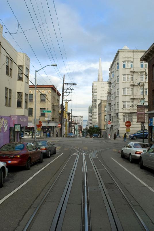 Cable car ride through the streets of San Francisco with a view out of the rear of the receding tracks and architecture of the buildings