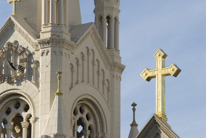 Detail of the spire of the Church of Saints Peter and Paul with the clock and cross in Washington square, San Francisco, California