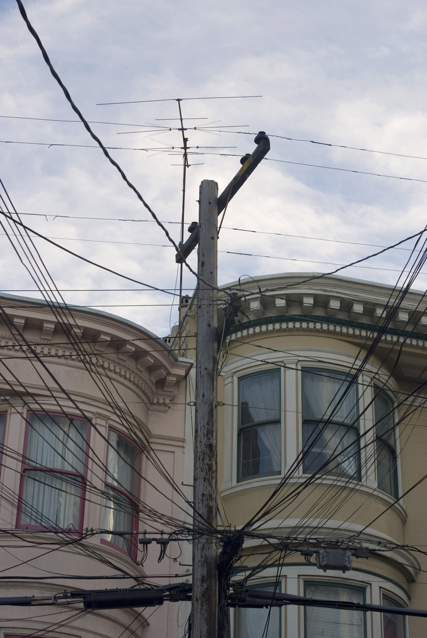 an image of San Francisco architecture with a view of the historical wooden facades of townhouses past a spaghetti junction electricity pole