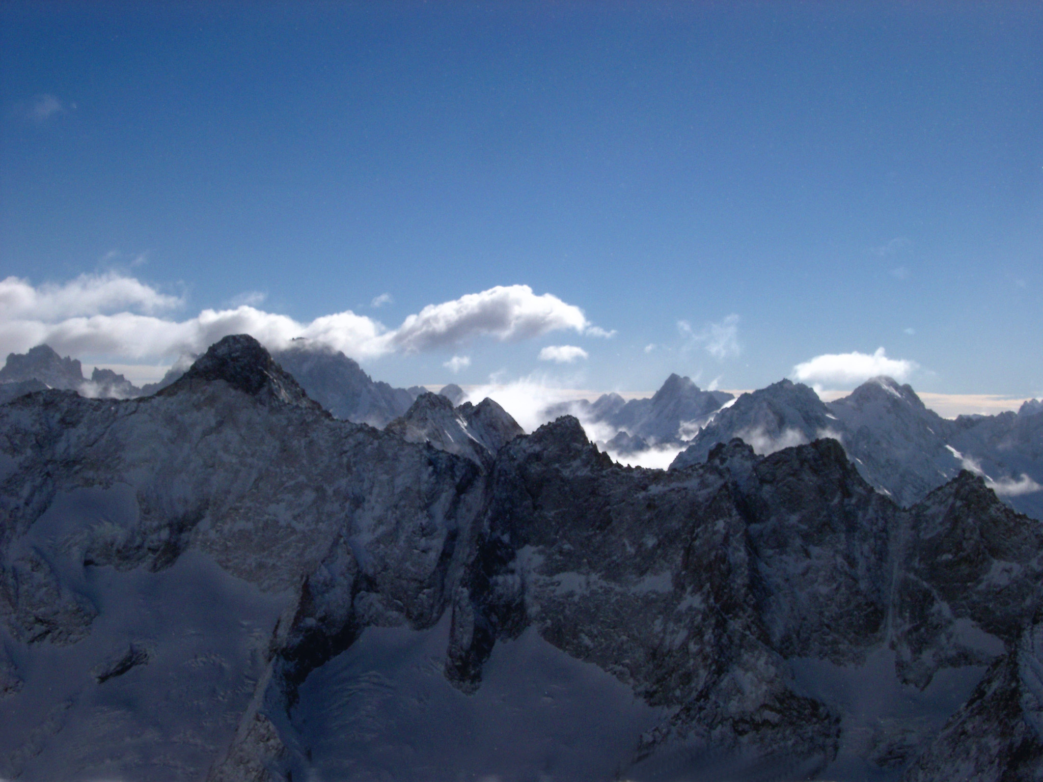 an image of High rugged alpine peaks in France in winter with fluffy white clouds above in a blue sunny sky