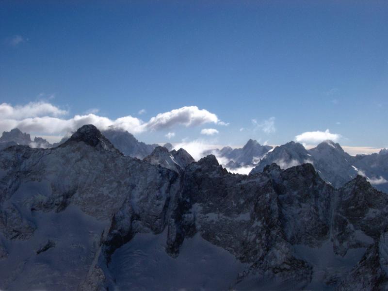 High rugged alpine peaks in France in winter with fluffy white clouds above in a blue sunny sky