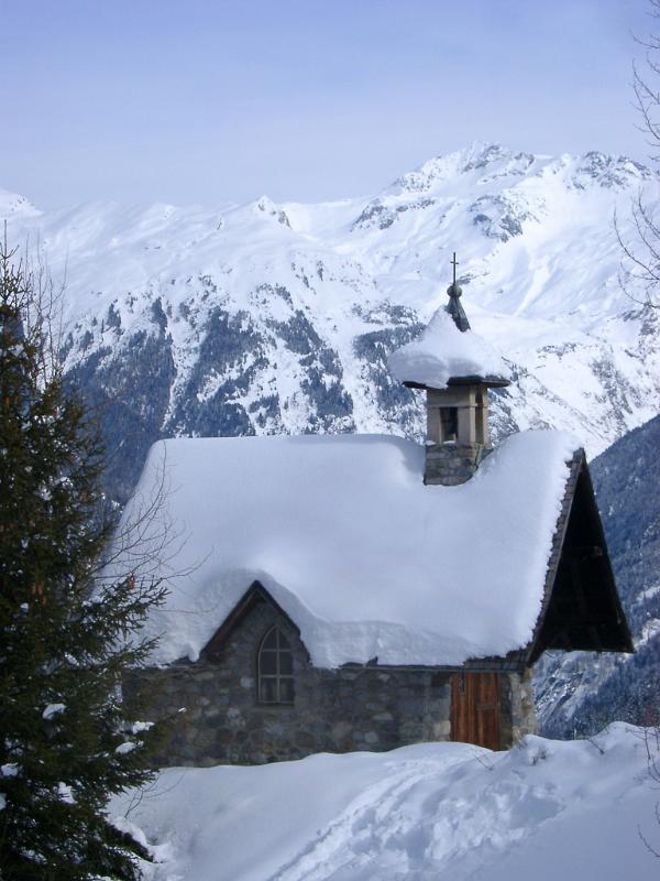 Historic Small Architectural Christian Church Building Filled with Snow, Captured with Huge Mountain on Background During Winter Season.